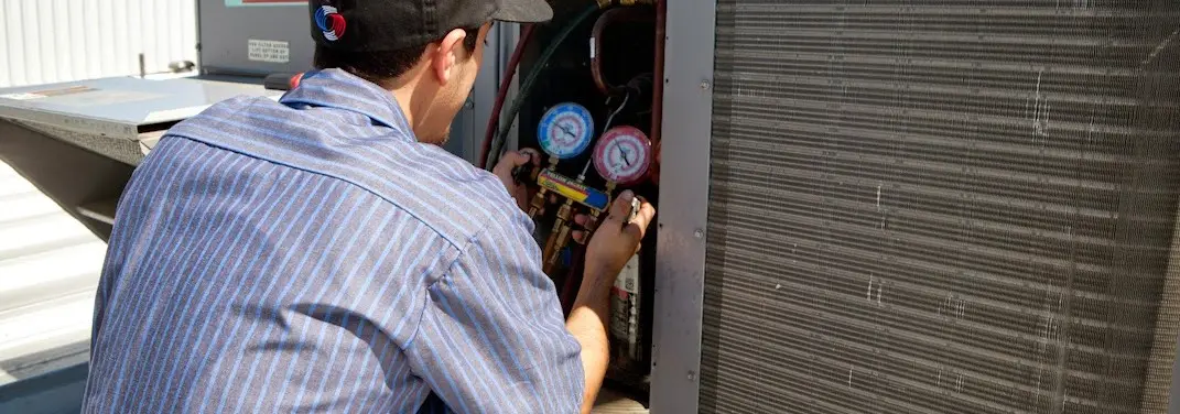 HVAC technician servicing a condenser unit in Poplar Grove