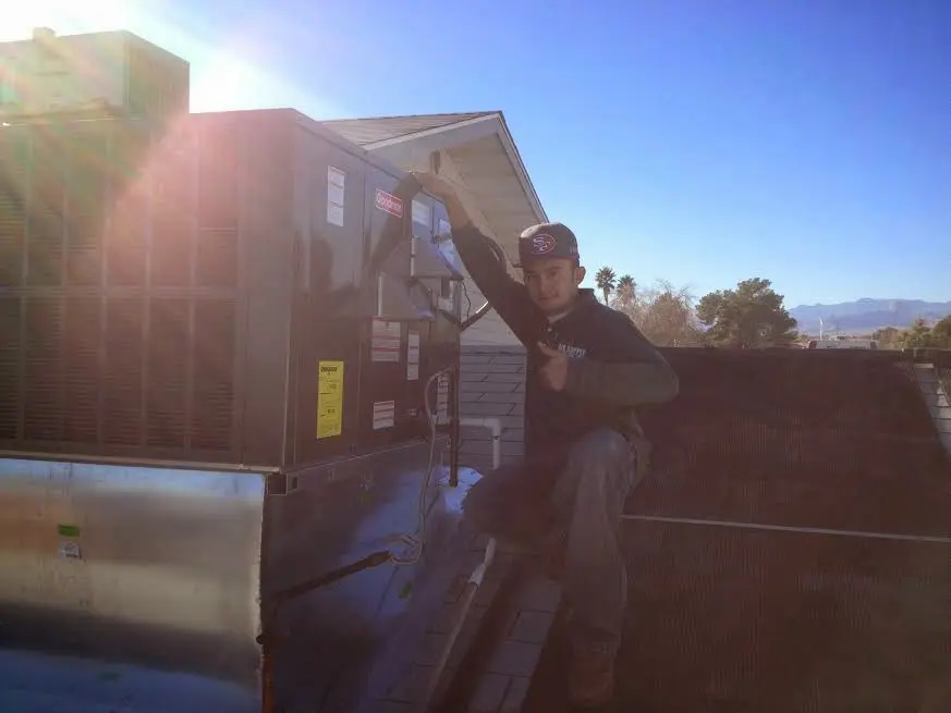 HVAC technician performing AC Tune-Up on a rooftop unit in Poplar Grove